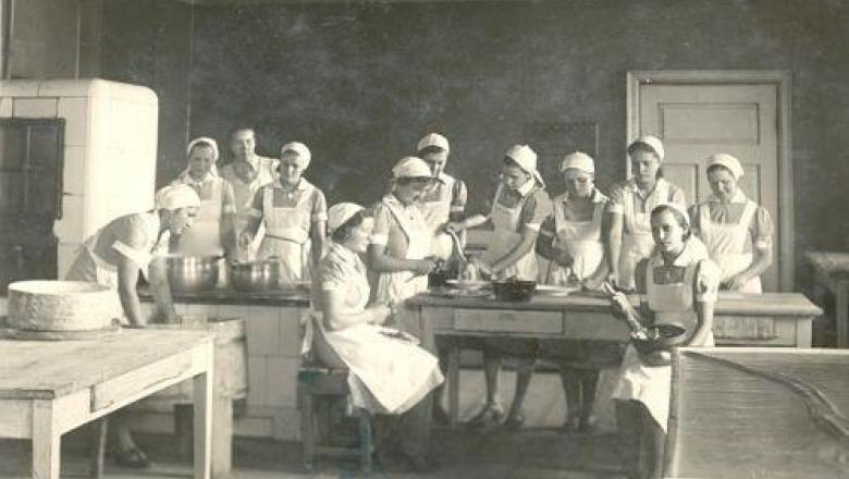 Palju naisi köögis valgete kitlite ja rätikutega  (mustvalge pilt)